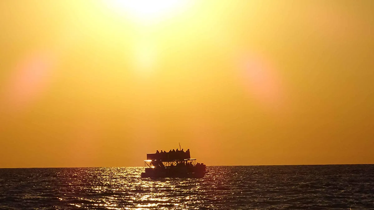 A double-deck catamaran on St. Andrews Bay at sunset on a Shell Island dolphin tour from Panama City Beach, Florida