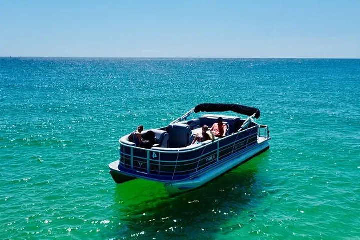 A pontoon boat anchored on clear green water on a full-day Shell Island pontoon rental from Panama City Beach, Florida