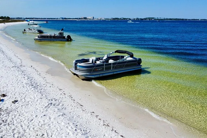 A pontoon boat pulled up on the white sand on a half-day Shell Island pontoon rental from Panama City Beach, Florida
