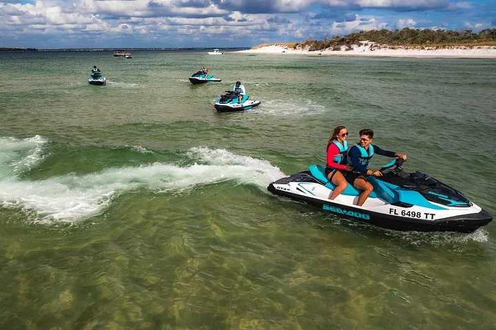 A guide and riders on jet skis near the shore on a Shell Island jet ski dolphin tour from Panama City Beach, Florida