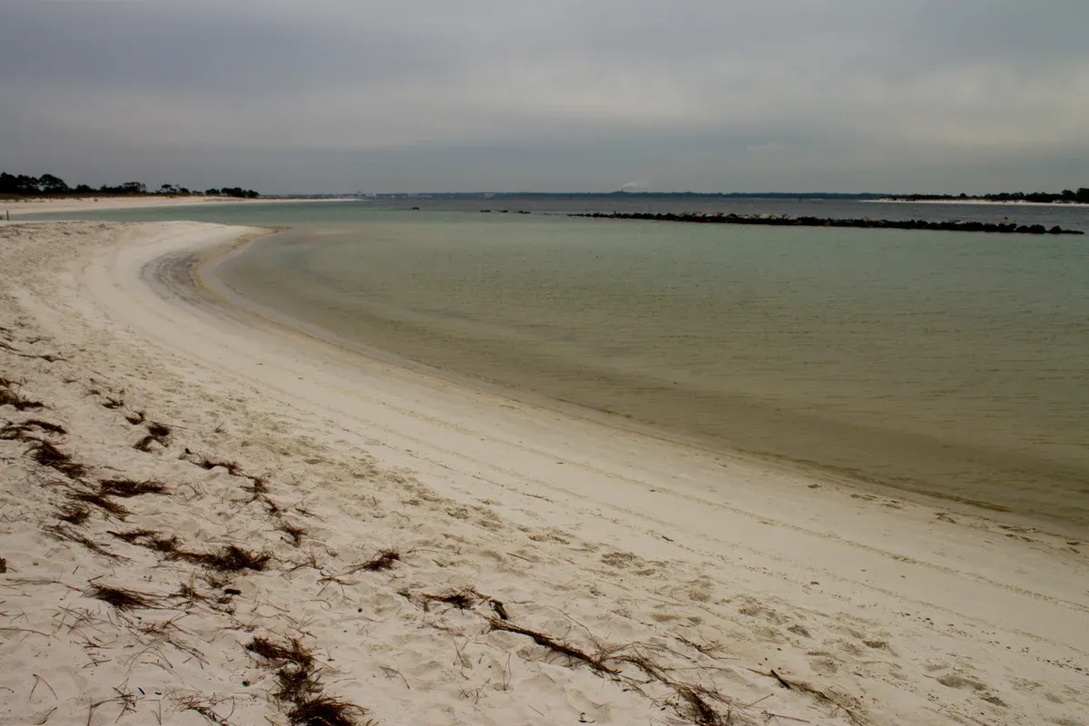 Calm inlet and pale sand beach at St. Andrews State Park with Panama City in the distance, near the Shell Island dolphin tour docks in Panama City Beach
